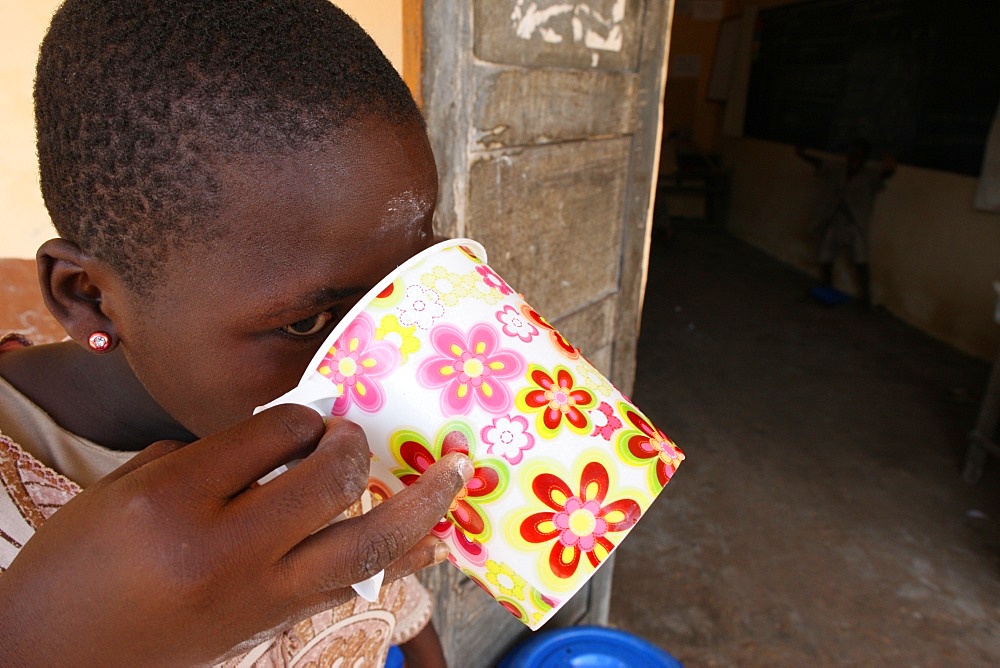 Girl drinking water, Lome, Togo, West Africa, Africa