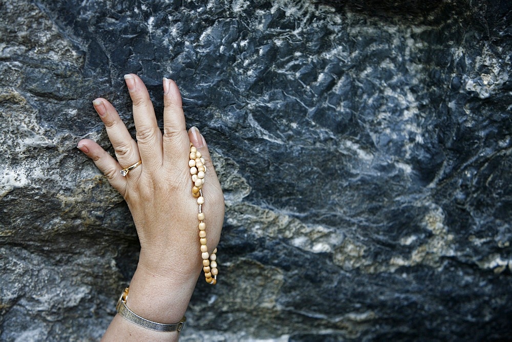 Pilgrim touching the Lourdes grotto, Lourdes, Hautes Pyrenees, France, Europe