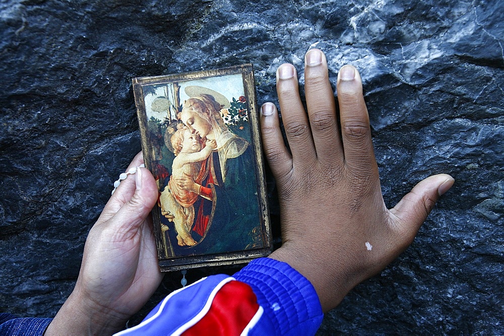 Pilgrims touching the Lourdes grotto, Lourdes, Hautes Pyrenees, France, Europe