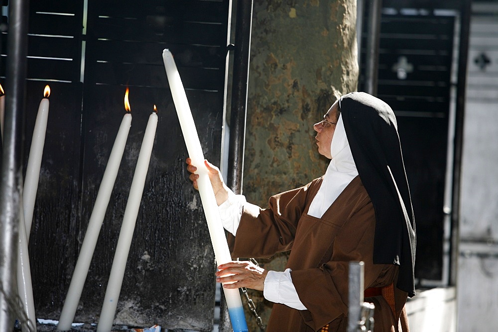 Nun lighting a candle at the Lourdes shrine, Lourdes, Hautes Pyrenees, France, Europe