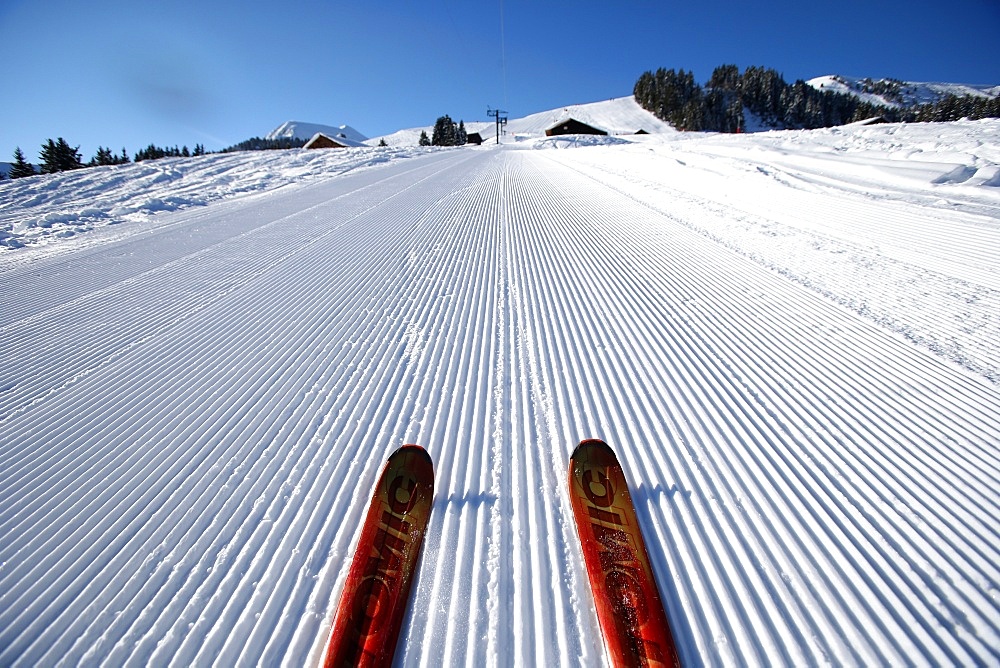 Red pair of ski in snow, groomed ski piste in the French Alps, Haute-Savoie, France, Europe