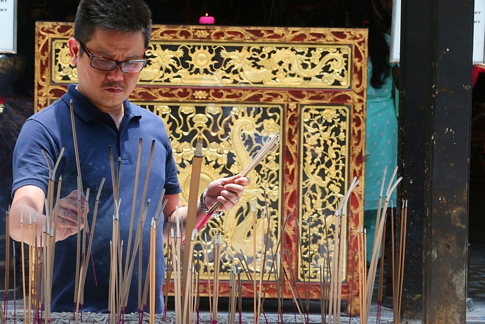 A Chinese man praying and offering incense, Thian Hock Keng Temple, Singapore, Southeast Asia, Asia