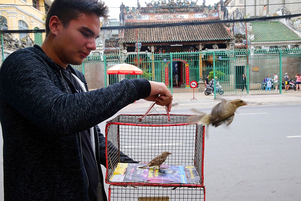 Man releases sparrow, Taoist temple, Phuoc An Hoi Quan Pagoda, Ho Chi Minh City, Vietnam, Indochina, Southeast Asia, Asia