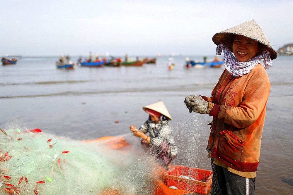 Fishermen and women repairing fishing nets at Tam Duong beach, Vung Tau, Vietnam, Indochina, Southeast Asia, Asia