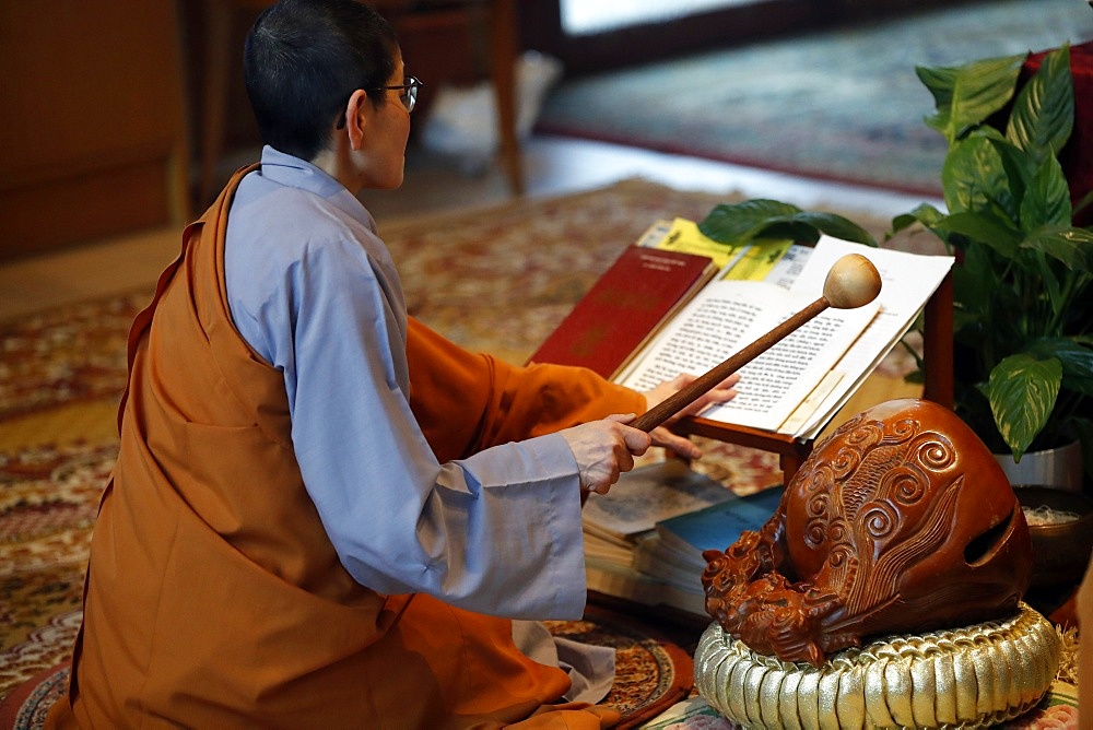 Monk at Buddhist ceremony, playing on a wooden fish (percussion instrument), Chua Tu An Buddhist temple, Haute Savoie, France, Europe