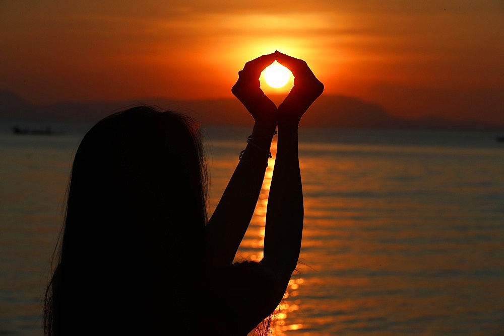 Silhouette of a woman standing by the sea at sunset, Kep, Cambodia, Indochina, Southeast Asia, Asia