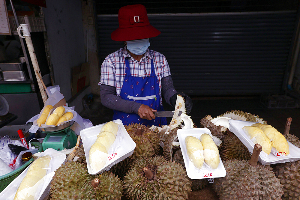 A woman prepares Durian fruit for sale at a street food stall popular with tourists and locals, Bangkok, Thailand, Southeast Asia, Asia