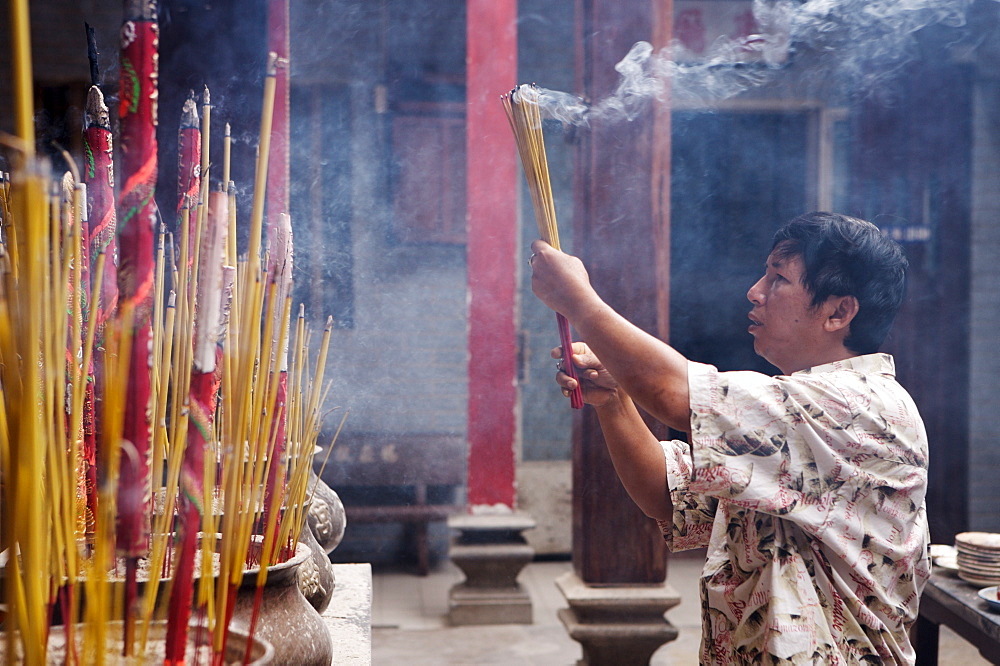 Local man making an offering in a Buddhist temple, Ho Chi Min City, Vietnam, Indochina, Southeast Asia, Asia