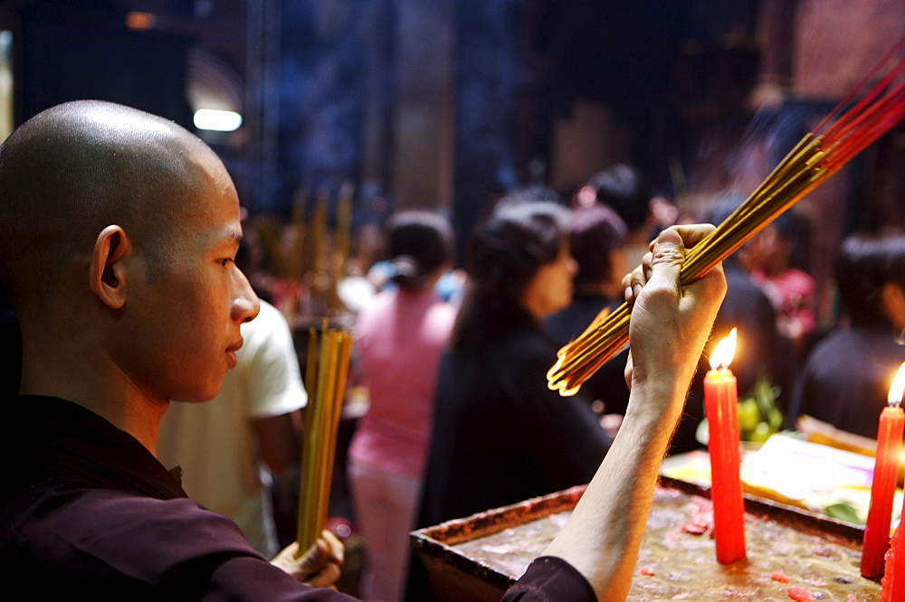 Monk lighting joss sticks during ceremony in a Buddhist temple, Ho Chi Min City, Vietnam, Indochina, Southeast Asia, Asia