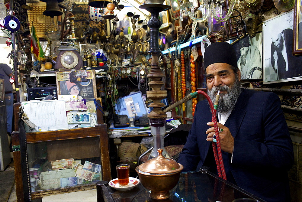 An old man smoking narguile in the bazaar of Isfahan, Iran, Middle East