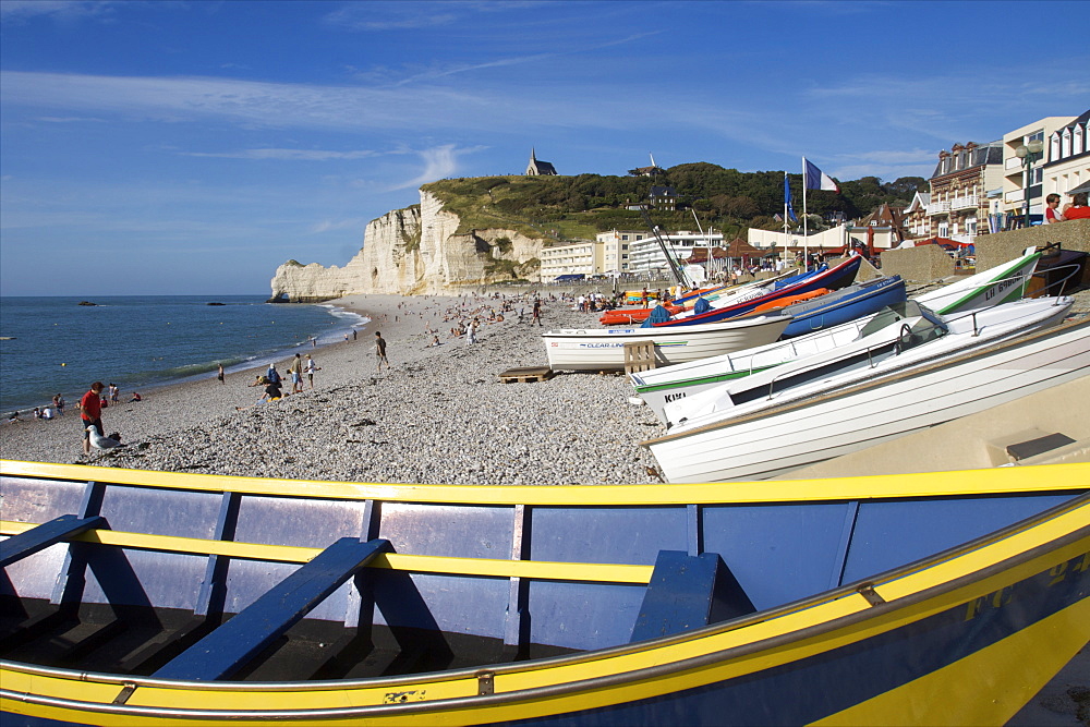 Boats drawn up on the great pebble beach of Etretat and the chapel of Notre-Dame de la Garde on the cliffs in the distance, Etretat, Seine Maritime, Normandy, France, Europe