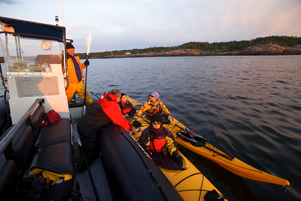 People in kayaks setting off to look for whales at dawn on the St. Lawrence River in the Marine Park of the Saguenay Saint-Laurent, Les Bergeronnes, Quebec Canada, North America