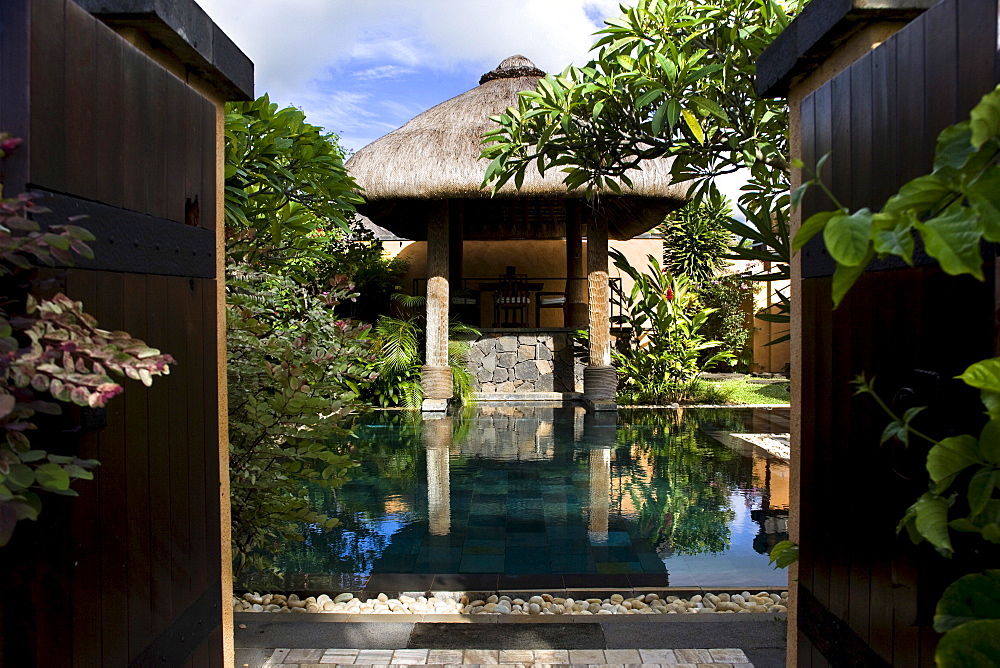 Outdoor swimming pool within a walled garden with thatched loggia, Baie aux Tortues, Pointe aux Pimentes, Mauritius, Africa