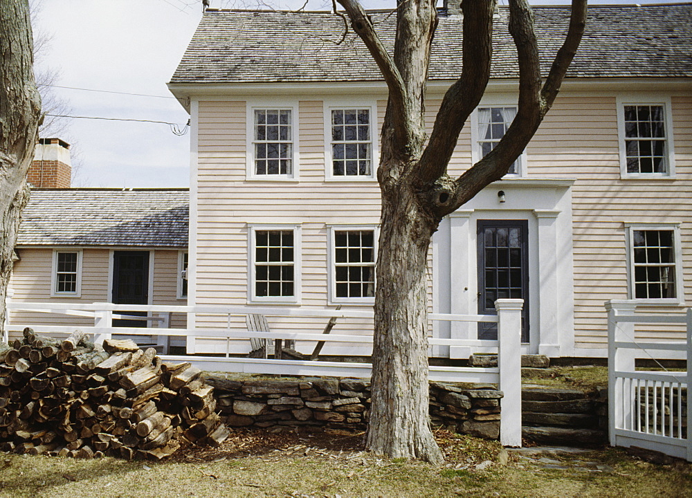 Late 18th or early 19th century timber frame clapboard farmhouse in winter, log pile of firewood, Lyme, Connecticut, New England, United States of America, North America