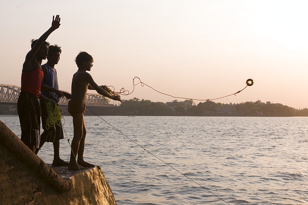 Young boys fishing for metal coins in the Howrah River, Kolkata (Calcutta), West Bengal, India, Asia