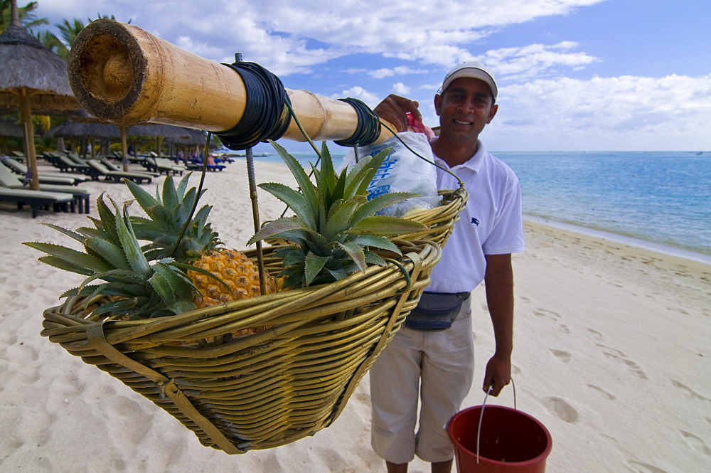 Man selling pineapples on the beach of the Beachcomber Le Paradis five star hotel, Mauritius, Indian Ocean, Africa