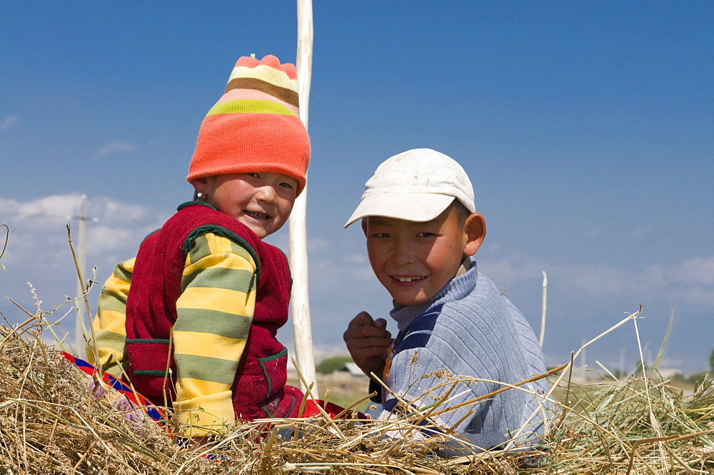 Two young kids on a carrier loaded with hay, Torugat Pass, Kyrgyzstan, Central Asia, Asia