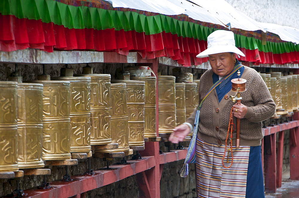 Old woman walking along the praying wheels, Potala, Lhasa,Tibet, China, Asia