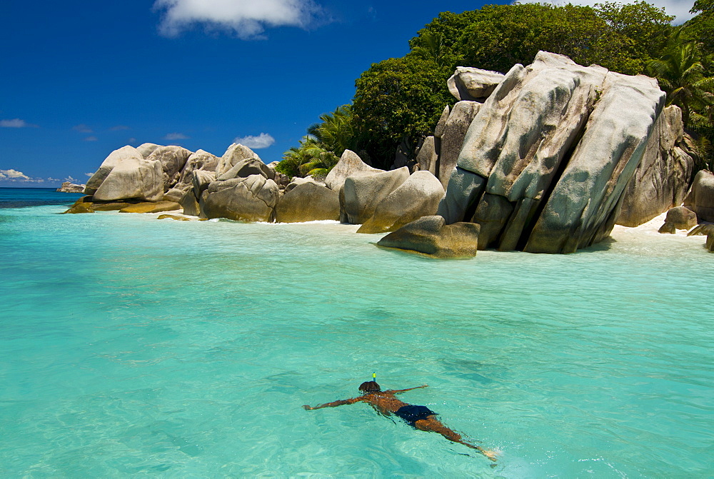 Local man swimming at the Granite rocks at Ile aux Cocos, Seychelles, Indian Ocean, Africa