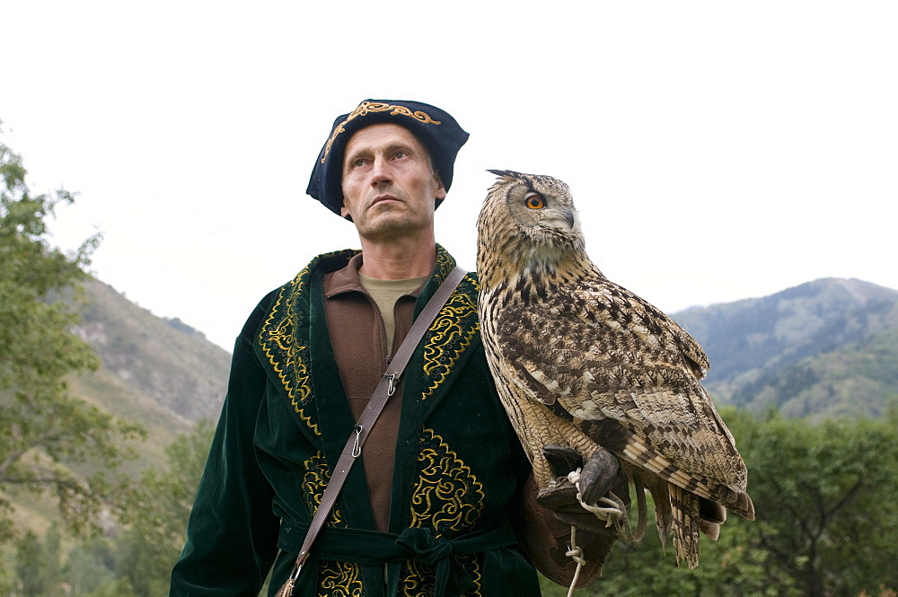 Kyrgyz eagle hunter with a rock eagle-owl (Bubo bengalensis), Sunkar Eagle Farm, Kazakhstan, Central Asia