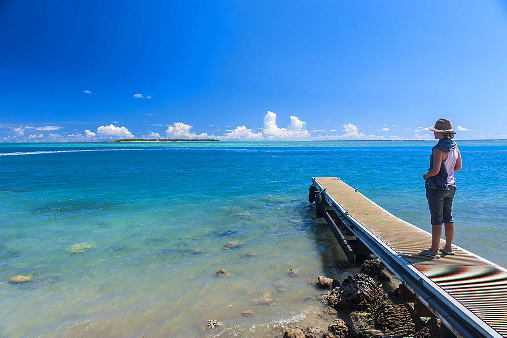 Tourist standing on a little pier with Cocos Island in the distance, Guam, US Territory, Central Pacific, Pacific