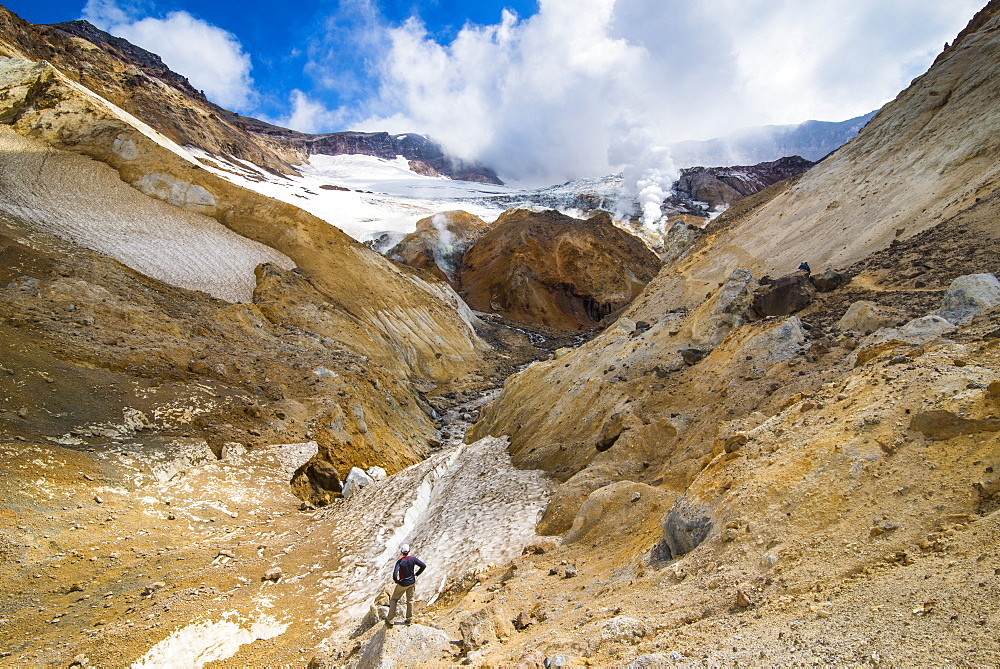 Tourist looking at smoking fumaroles on Mutnovsky volcano, Kamchatka, Russia, Eurasia 