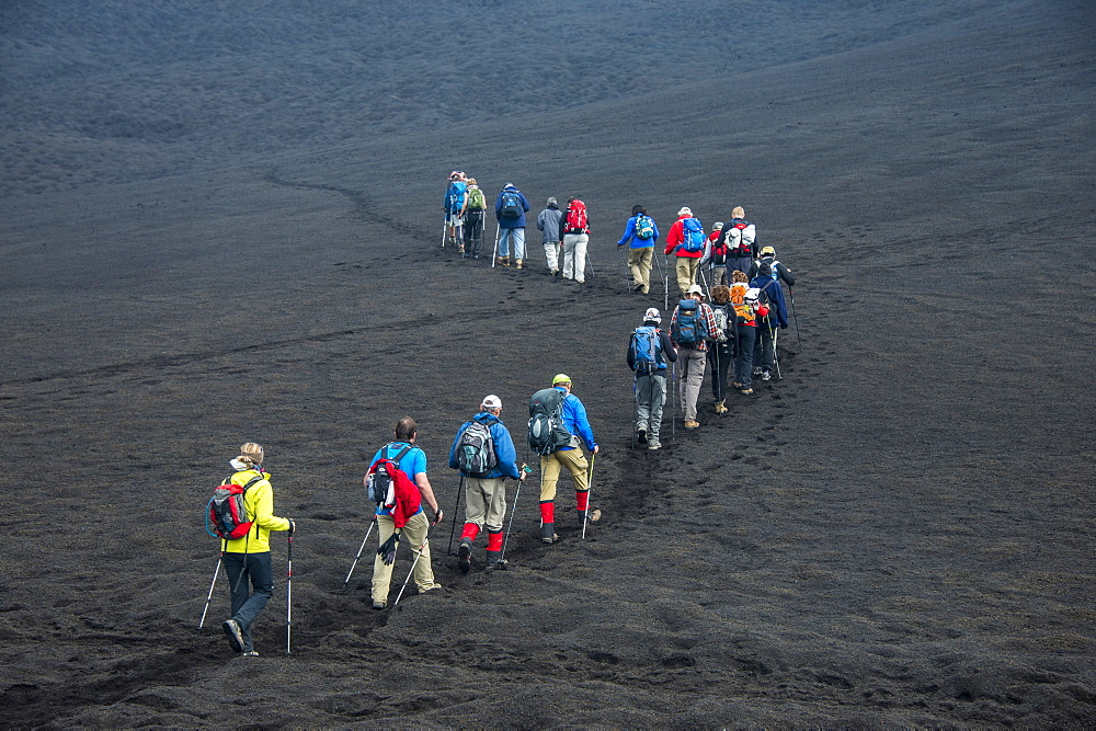 Tourists walking in a line through the lava sands of the Tolbachik volcano, Kamchatka, Russia, Eurasia