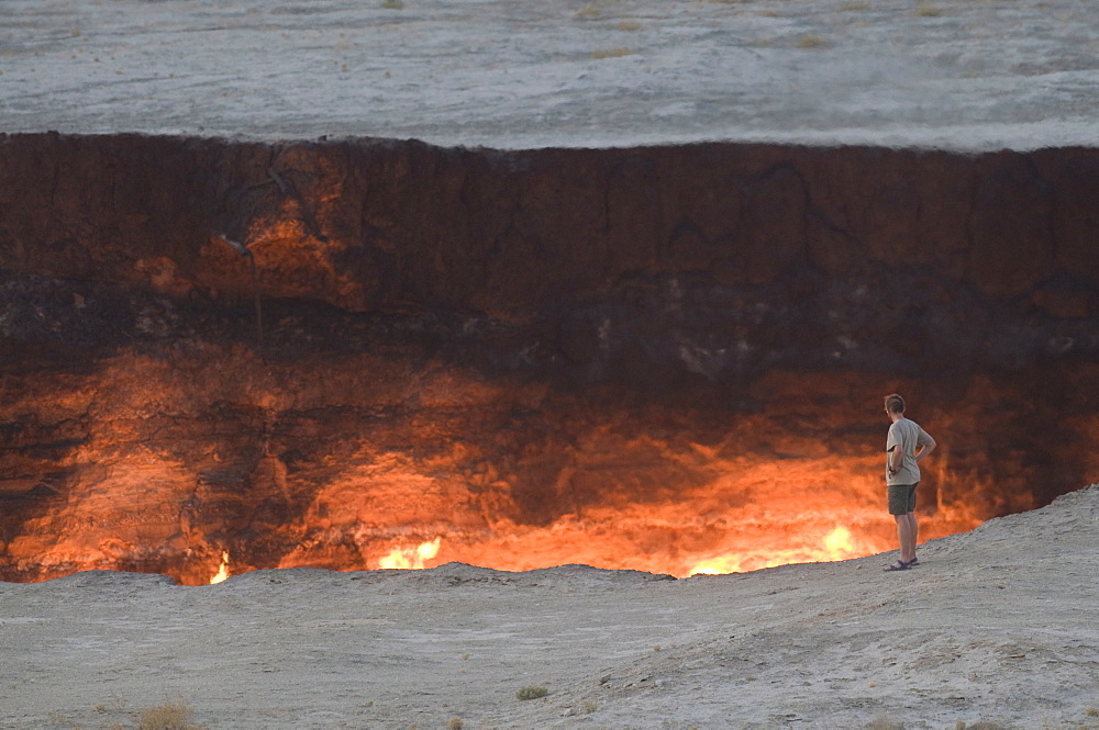 Tourist standing on the edge of the Darvaza Gas crater, Turkmenistan, Central Asia, Asia