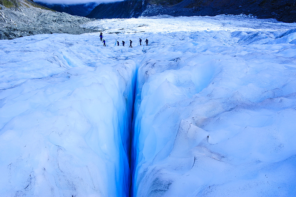 Tourists hiking above a giant crack on Fox Glacier, Westland Tai Poutini National Park, South Island, New Zealand, Pacific