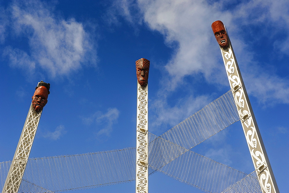 Hand carved wooden mask on huge piles at the entrance of the Te Puia Maori Cultural Center, Rotorura, North Island, New Zealand, Pacific