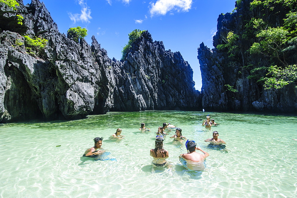 Tourists in the hidden bay with crystal clear water in  the Bacuit archipelago, Palawan, Philippines, Southeast Asia, Asia