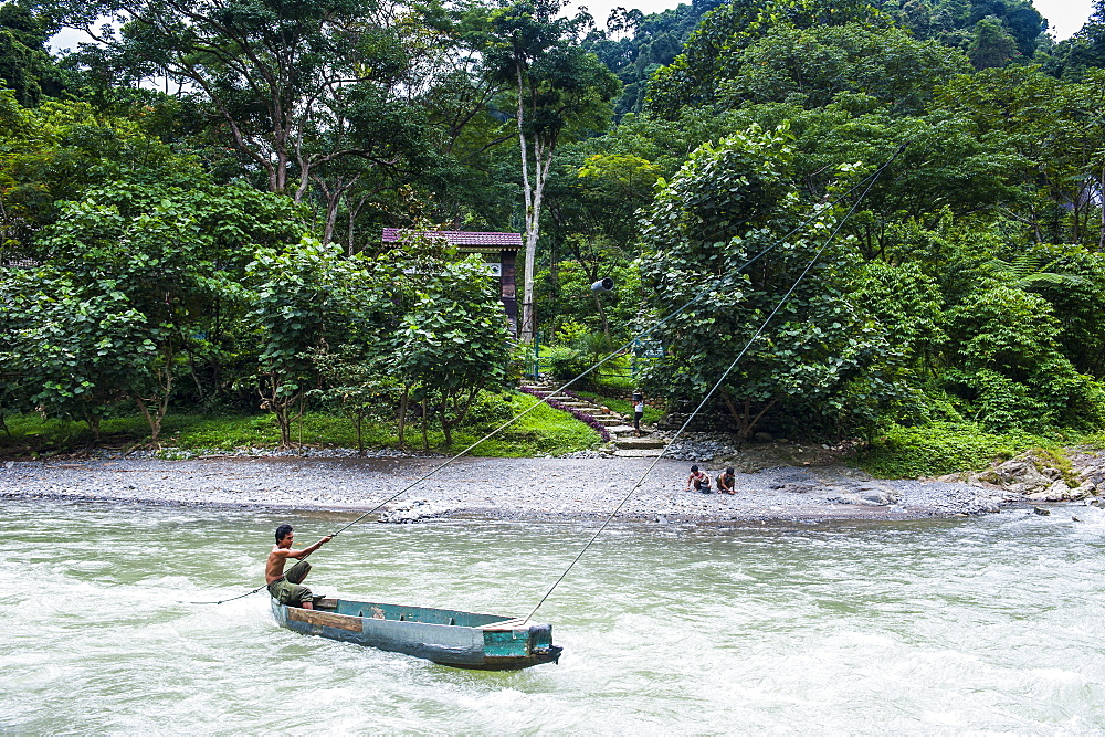 Man pulling a canoe on the Bohorok River to transport tourist to the Bukit Lawang Orang Utan Rehabilitation station, Sumatra, Indonesia, Southeast Asia, Asia