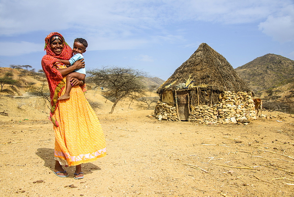 Mother with her son in front of a traditional hut in the highlands of Eritrea, Africa