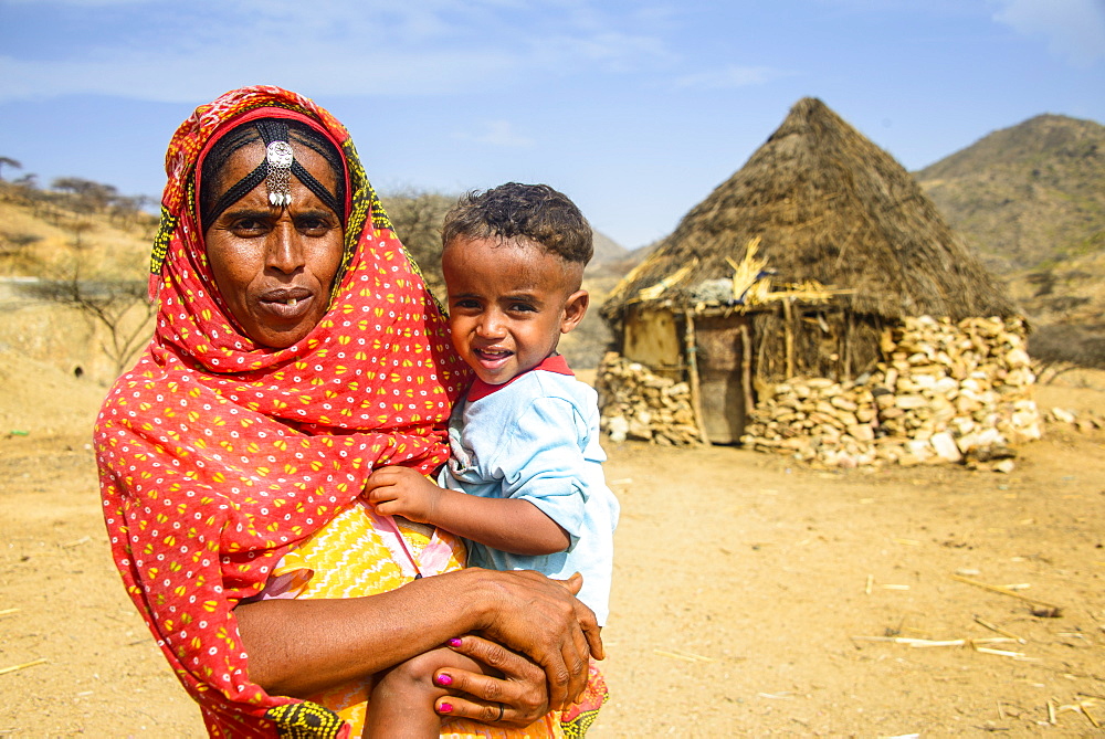 Mother with her son in front of a traditional hut in the highlands of Eritrea, Africa