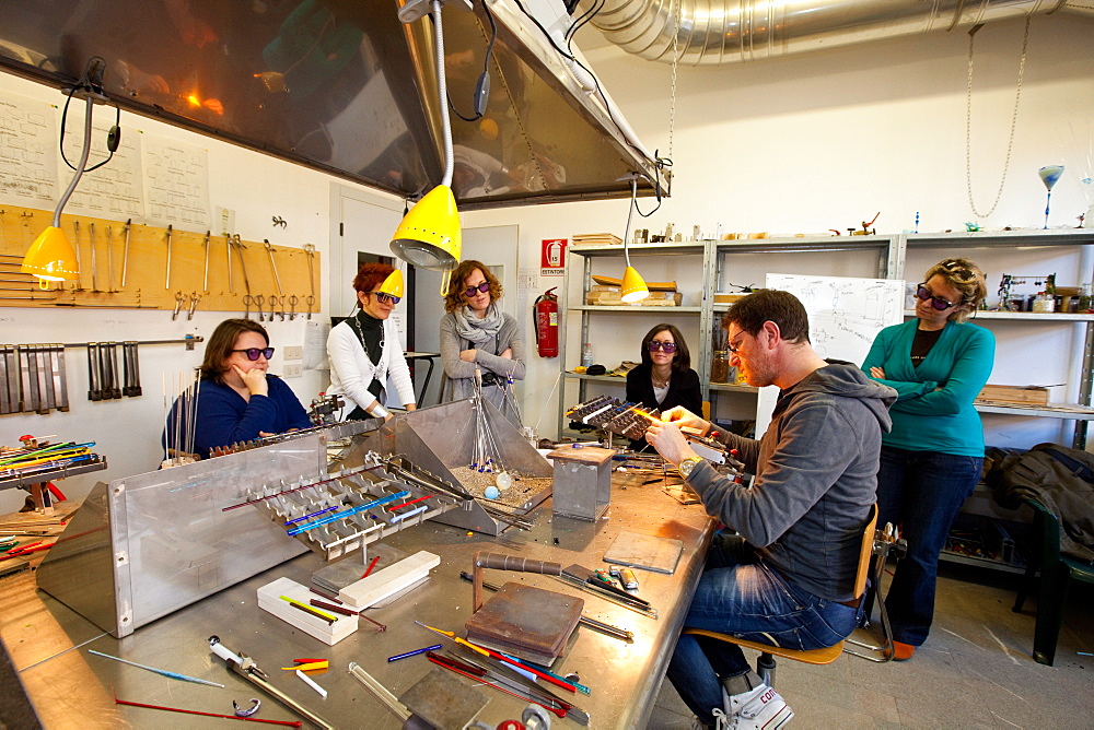 Muranese instructor teaching to a group of students the lampworking technique to make glass beads, Abate Zanetti glass school, Murano island, Venice, Veneto, Italy, Europe