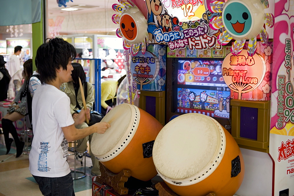 Boy playing a Japanese taiko drum video game at a game center, Japan, Asia