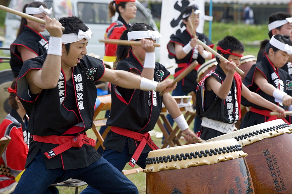 Energetic group of drummers beating Japanese taiko drums during an outdoor performance, Japan, Asia