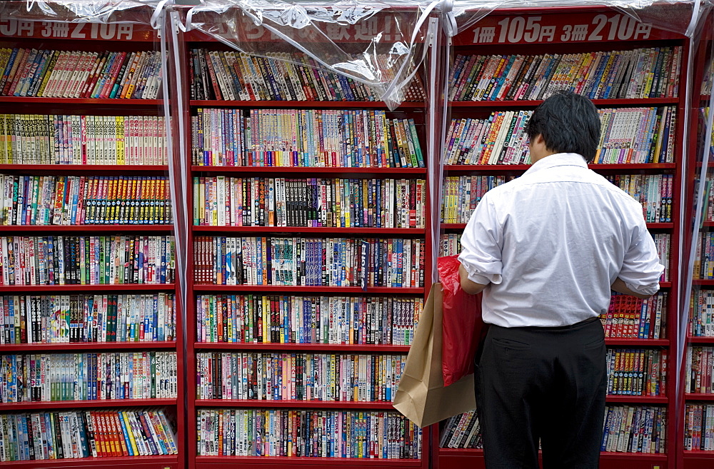 Man browsing Japanese manga comic books at a shop in Osaka, Japan, Asia