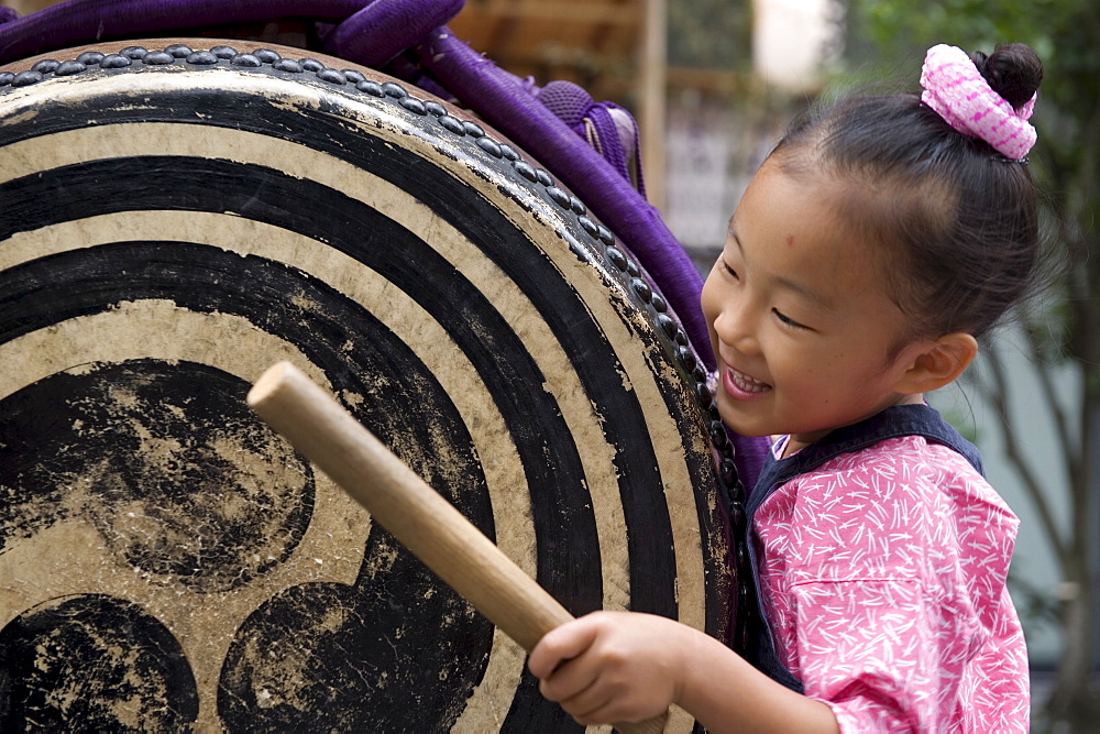 A little girl getting into the spirit of things with a taiko drum at the Sanja Festival in Asakusa, Tokyo, Japan, Asia