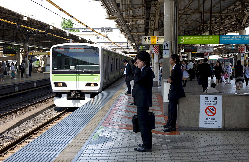 Businessman waiting for the Yamanote loop line train just arriving at the JR Ueno railway station in Tokyo, Japan, Asia