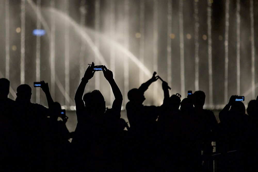 Tourists photograph the water fountain in the Burj Khalifa lake with their phones, Dubai, United Arab Emirates, Middle East 