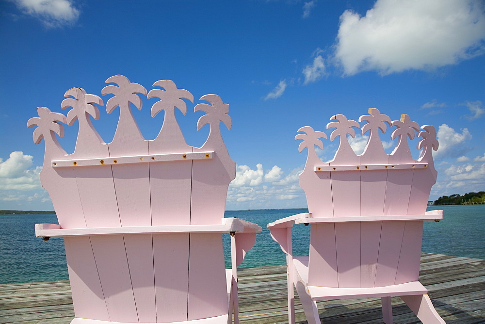 Wooden pink beach chairs with backs carved in the shape of palm trees