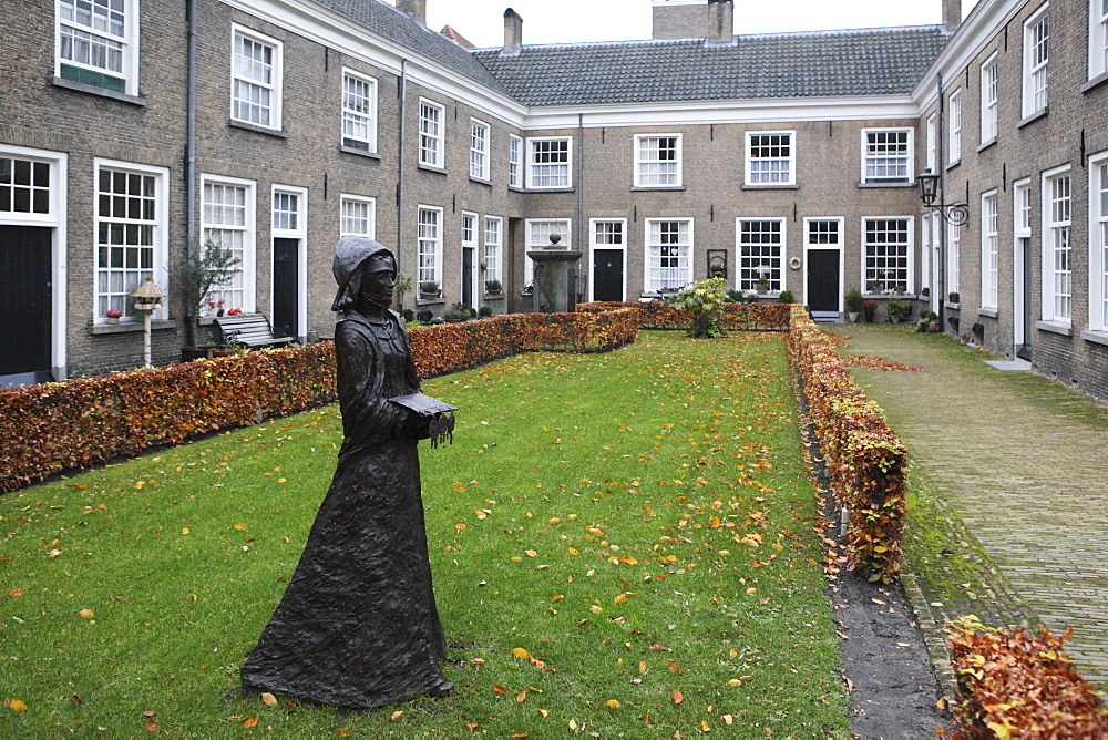 A statue of a nun stands in a courtyard of historic housing for women at the Begijnhof (Beguinage), Breda, Noord-Brabant, Netherlands, Europe