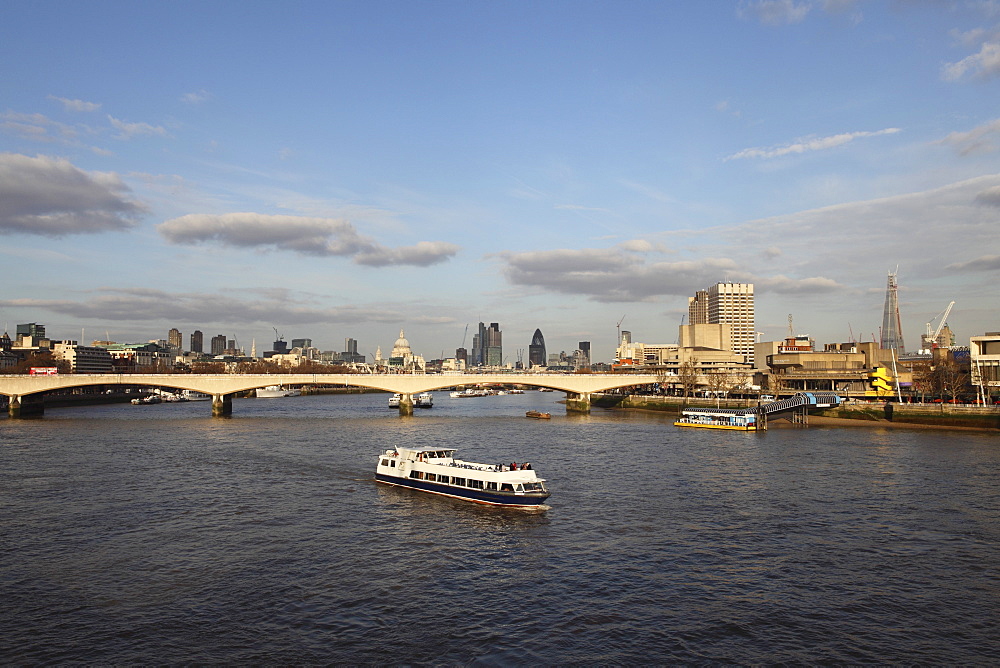 A cruise boat on River Thames, ahead of Waterloo Bridge and the skyline of the City, from Westminster, London, England, United Kingdom, Europe