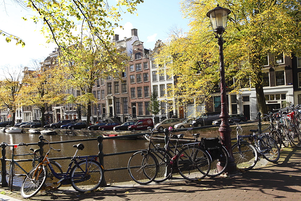 Bicycles chained to railings by a canal on a sunny day in Amsterdam, The Netherlands, Europe