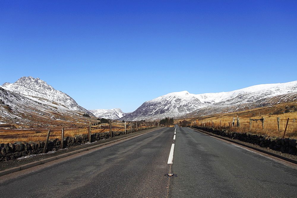 The A5 road runs through past snow-capped mountains in Snowdonia National Park, Wales, United Kingdom, Europe