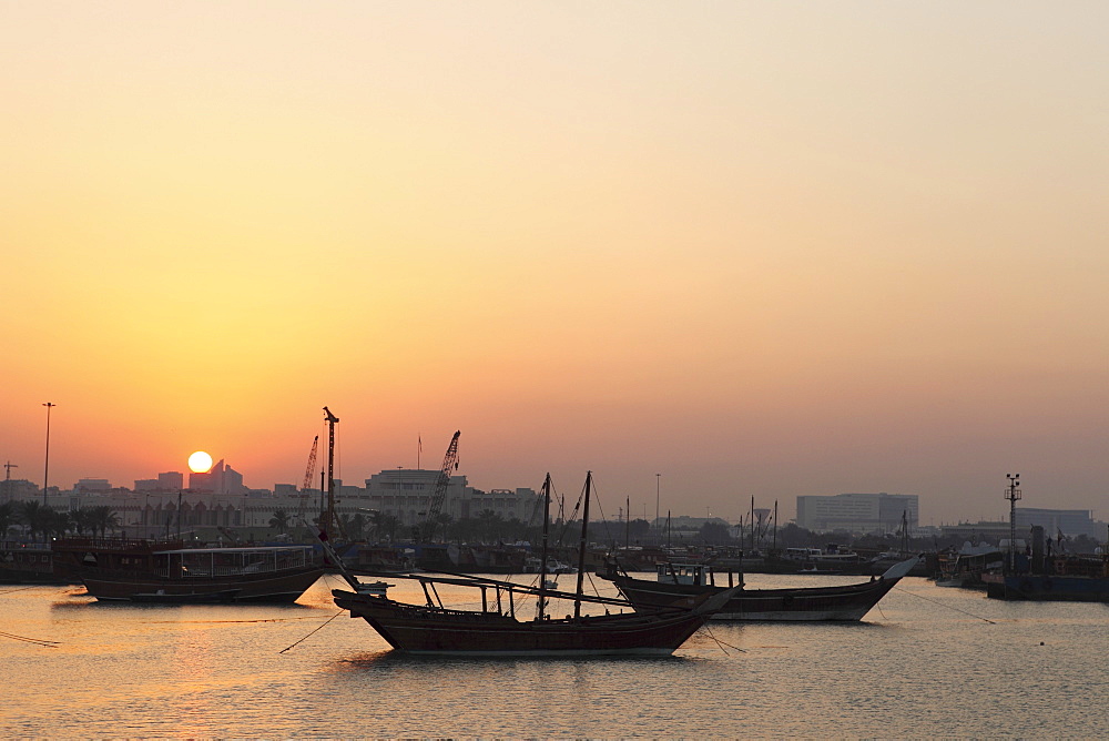 Traditional wooden dhow boats in the Corniche marina, at sunset in Doha, Qatar, Middle East