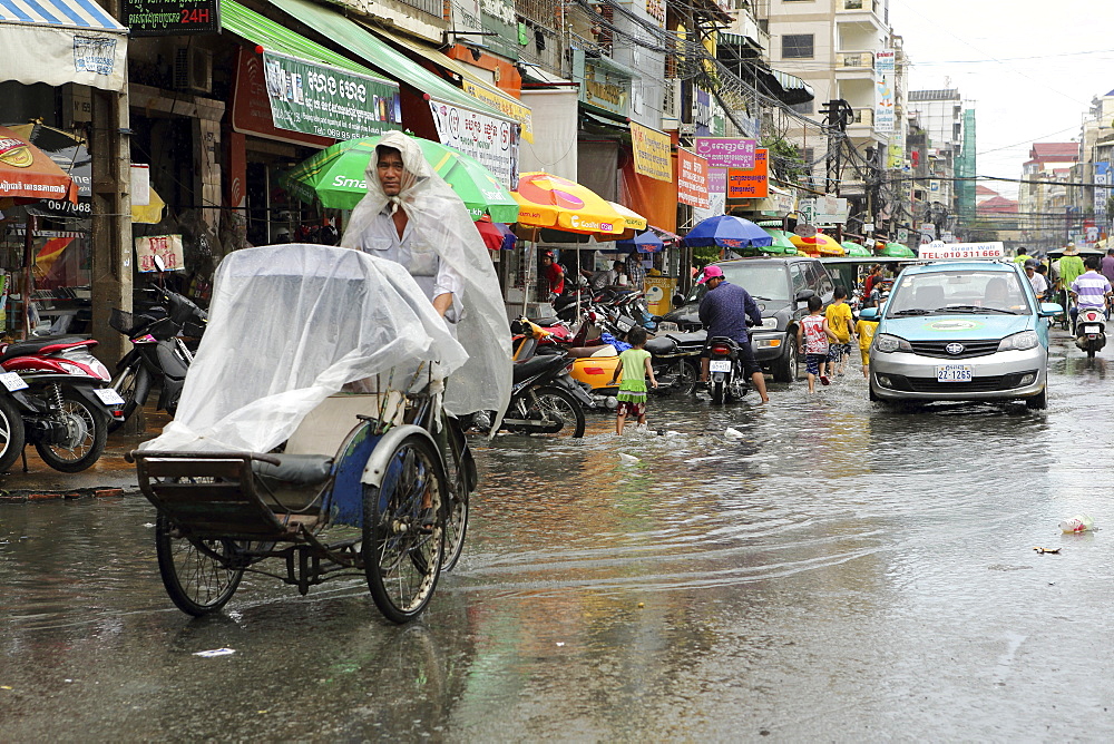 Traffice, including a cyclo and taxi, on a waterlogged street during the monsoon season in Phnom Penh, Cambodia, Indochina, Southeast Asia, Asia