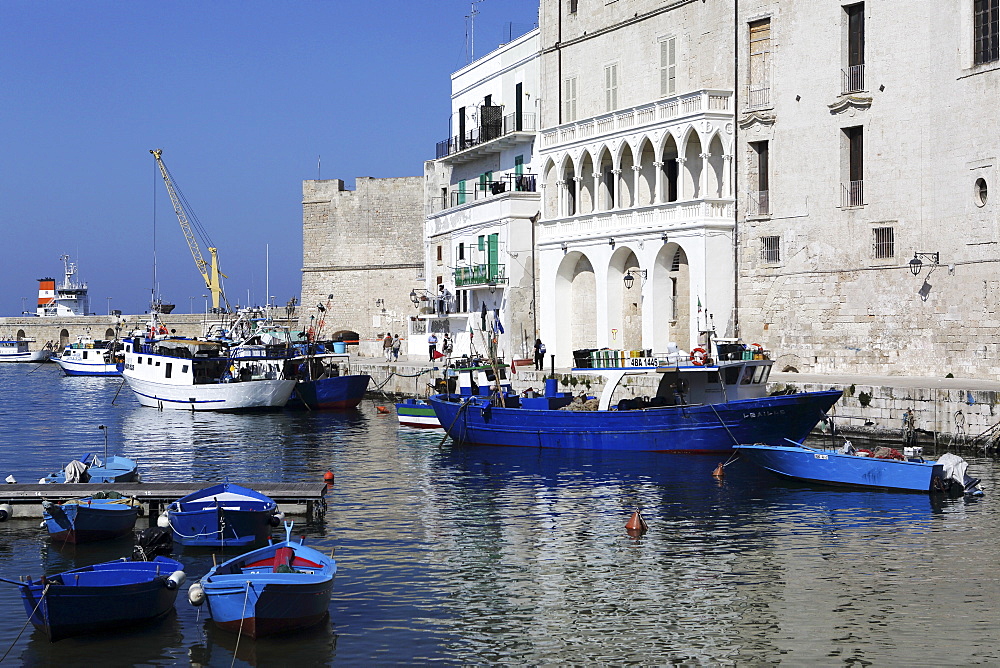 Blue wooden boats and fishing vessels in the walled harbour of Monopoli in Apulia, Italy, Europe