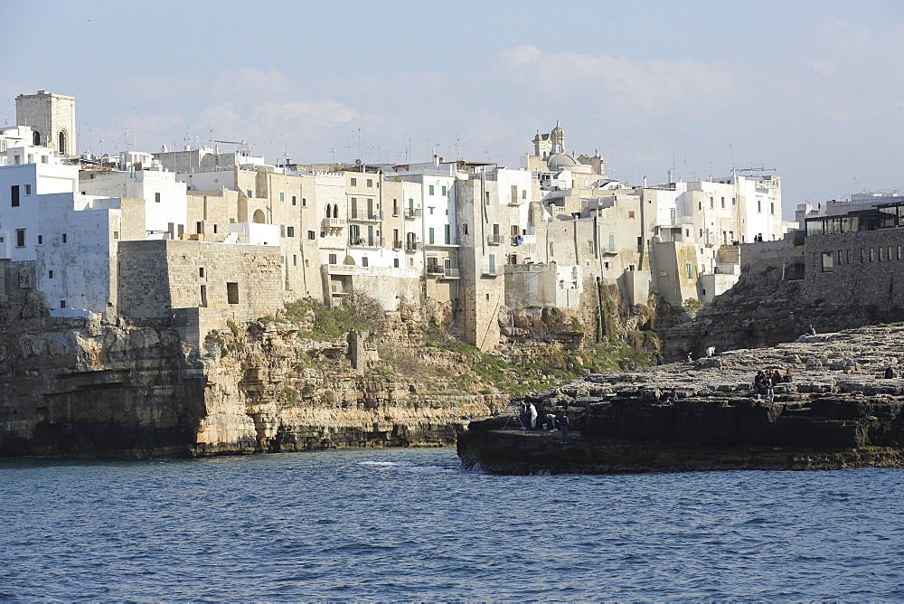 Clifftop houses, built onto rocks, surround the natural cove forming the harbour of Polignano a Mare, Apulia, Italy, Europe